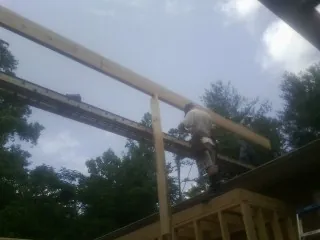 Carpenter setting a ridge beam over a new addition frame — Ice Dam Removal by Roofing Brothers in Pocasset